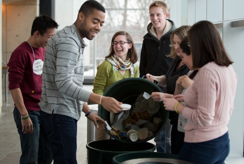 laughing students and staff working on composting