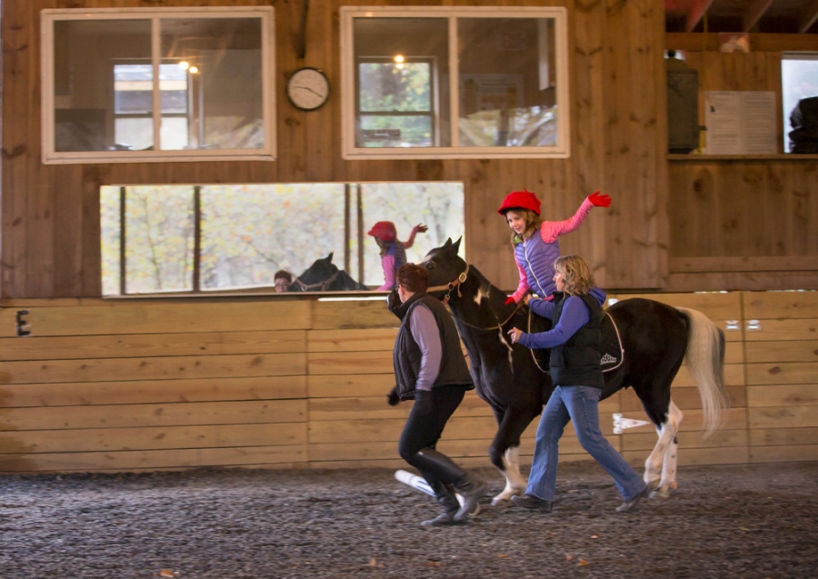 a young girl with a black horse moves along