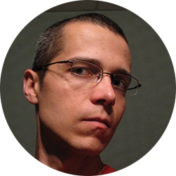 A man with glasses looks serious and angry.