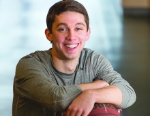 young man leans on a basketball sitting on a recycling bin