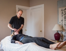 male practitioner performs acupuncture on female patient
